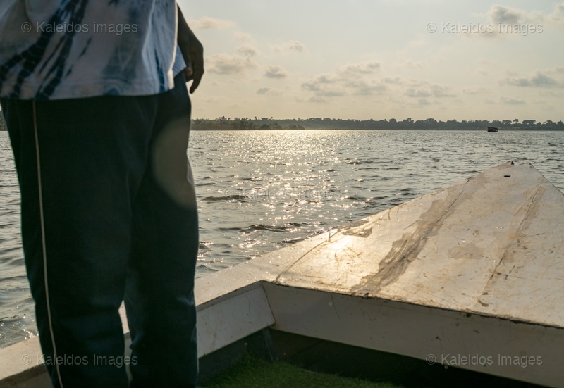 Lac Toho;Ouidah;Bénin;Afrique de l'Ouest;bateau;heure dorée;coucher de soleil;reflet de lumière;miroitement;homme sur bateau;proue;traversée;contemplation;contre-jour;voyage;Tarek Charara;Kaleidos;Kaleidos images;La parole à l'image