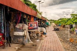 Allée-pavée;-Artisanat;-Bandeau-rouge;-Bénin;-Cotonou;-Échoppe;-Gbegamey;-Kaleidos;-Kaleidos-images;-La-parole-à-limage;-Marché-des-arts;-Tableau-peint;-Tarek-Charara;-Tissu;-Voie-ferrée